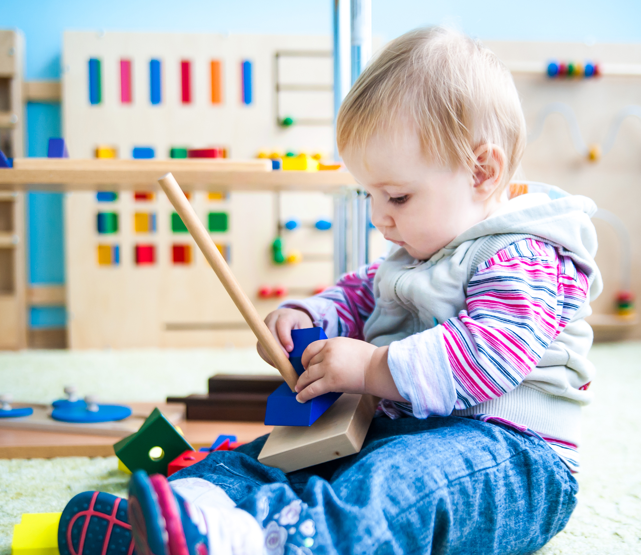 little girl in the classroom early development plays with numerous bright toys